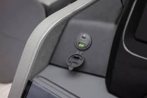 Close-up of a car interior showing a Catalina Elite charger port integrated into the dashboard. The port includes one standard USB slot and one USB-C slot, both illuminated by a green light. The charger is enclosed within a grey leather-like material and black textured panel.