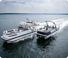 Two luxury pontoon boats glide side by side on a calm lake under a partly cloudy sky. Both boats have sleek, modern designs with spacious seating and are surrounded by open water with a distant shoreline visible on the horizon, epitomizing the ideal search for "pontoons near me.
