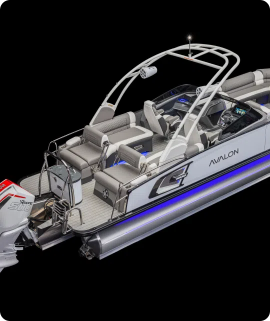 A modern pontoon boat with white and gray seating, labeled "Avalon" and "G." It features a sleek design, blue accent lighting along the sides, a powerful outboard motor, cup holders, multiple seating areas, a steering console with a screen, and sleek railings. Available now at your local pontoons dealer.