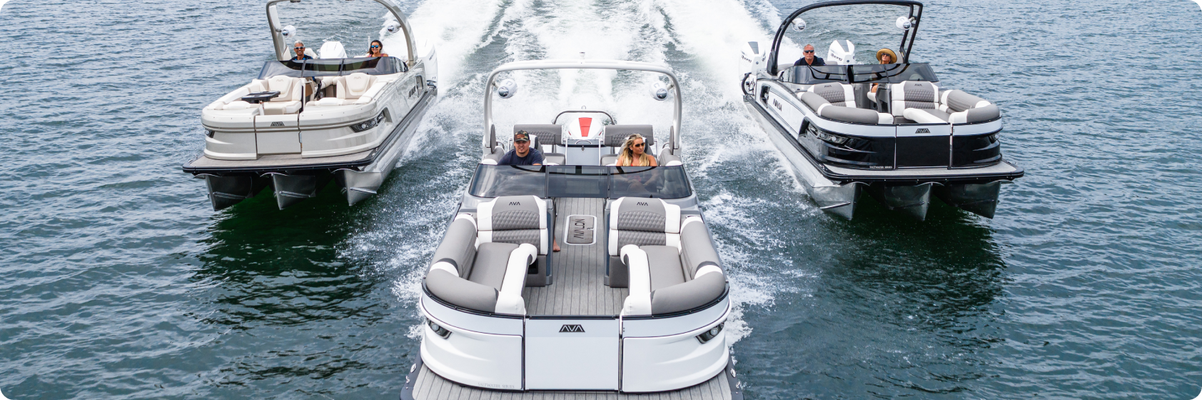 Three pontoon boats travel on the water side by side, each carrying several passengers enjoying a sunny day. The boats create white wakes as they move across the blue water. The central boat, reflecting its higher cost of pontoon boat quality, is slightly ahead of the others.