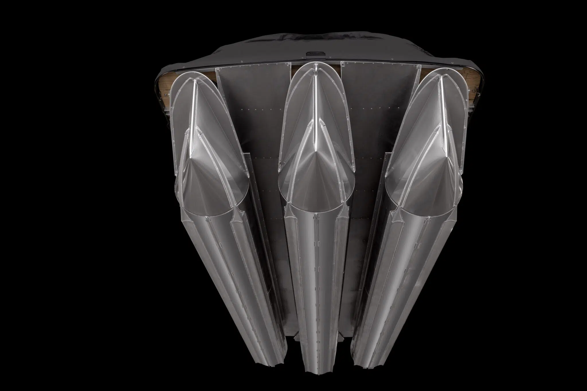 A view of the underside of a spacecraft with four large metallic engines or thrusters arranged side by side against a black background. The engines have a sleek and aerodynamic design.