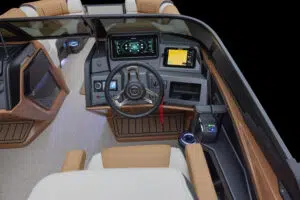 Interior view of the Catalina Cruise Rear Bench Windshield showcasing a contemporary boat cockpit with a steering wheel, digital control panels, GPS display, and brown-beige upholstered seating. The design features wood-like flooring and ambient lighting.