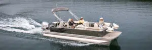 A pontoon boat, known for its lightweight design, gracefully glides across a calm body of blue water. With three people aboard, it boasts a sturdy Honda outboard motor and a protective canopy, perfectly mirroring the clear sky above.