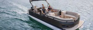 A group of friends enjoy a leisurely ride on a top pontoon boat brand, gliding over calm waters. With cushioned seats and a canopy for shade, the sun reflects off the water, creating a serene atmosphere.