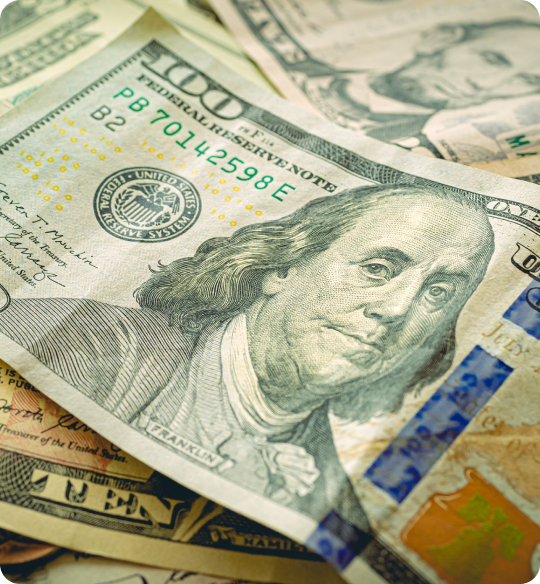 A close-up of a stack of U.S. hundred dollar bills featuring Benjamin Franklin, resembling the allure of top pontoon boat brands in their craftsmanship. The bills are arranged with the top one prominently displayed, showcasing intricate details and security features like the blue security strip.