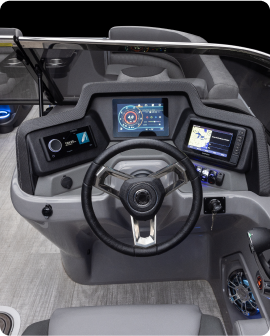 Close-up of a modern boat steering console on the new pontoon, featuring a central steering wheel, two digital displays showing navigational and system information, and various control buttons. The sleek console is thoughtfully designed, surrounded by comfortable seating for an enjoyable experience.